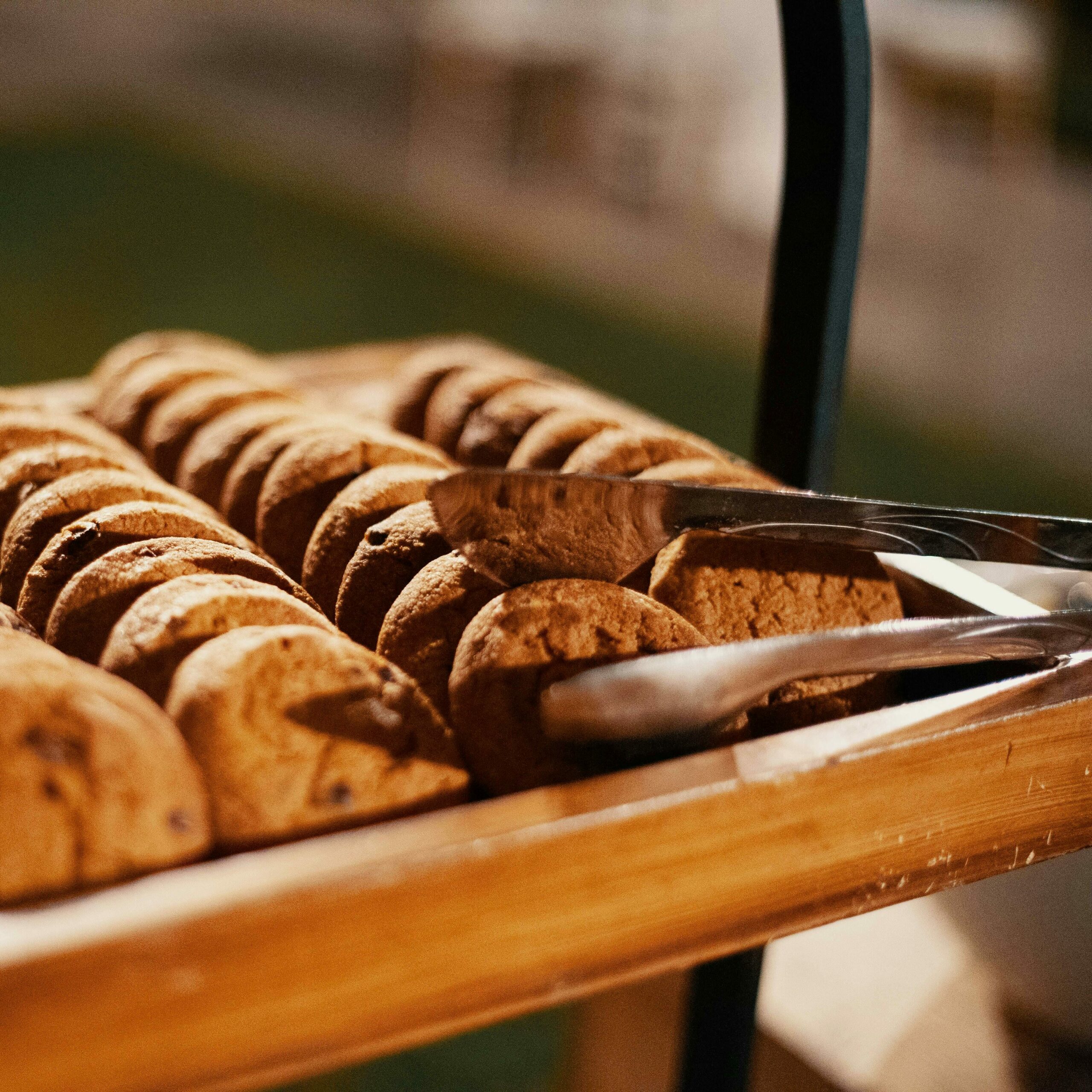 Close-up of freshly baked chocolate chip cookies on a wooden tray, indoors.