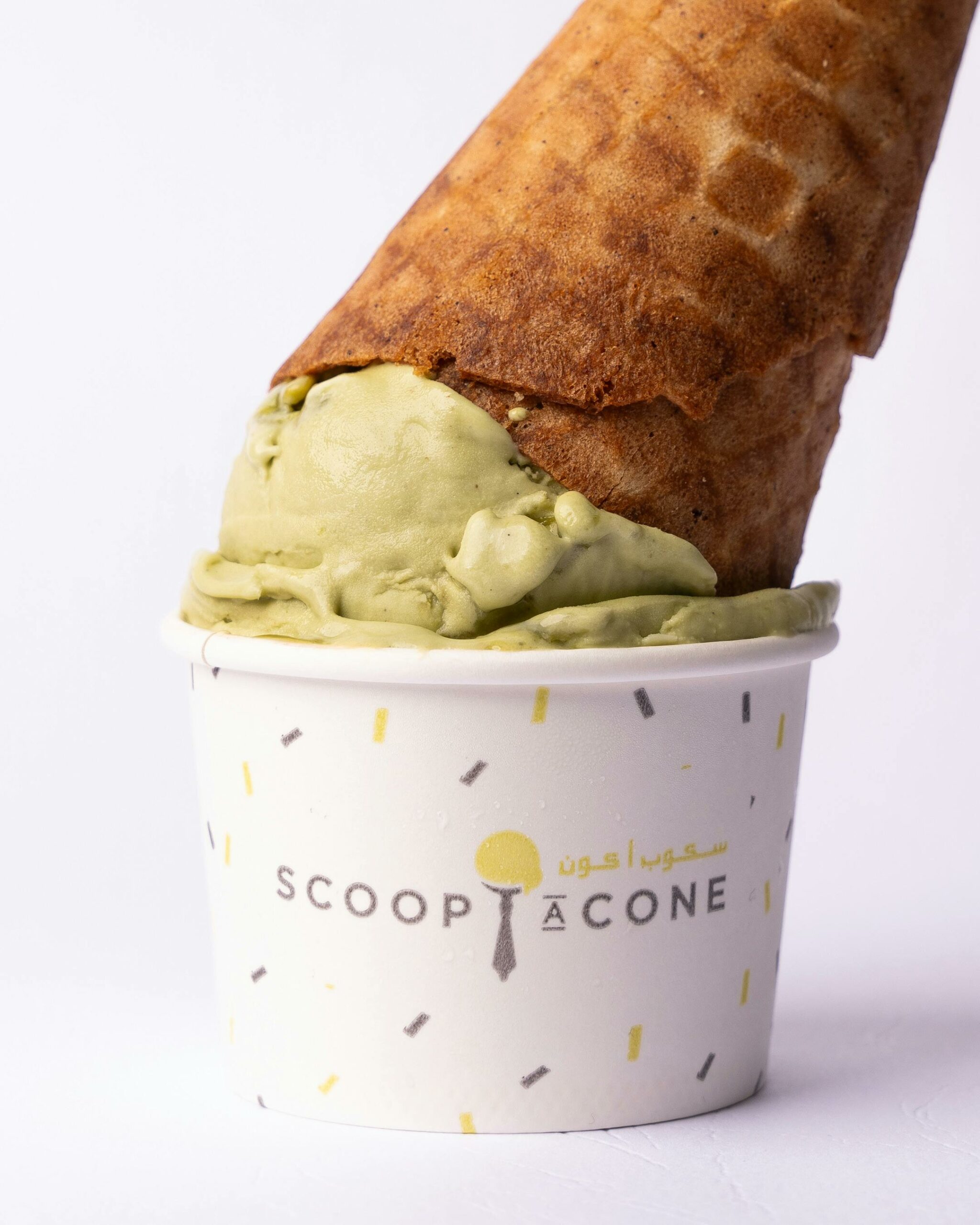 Appetizing pistachio ice cream cone placed upside down in a branded cup.